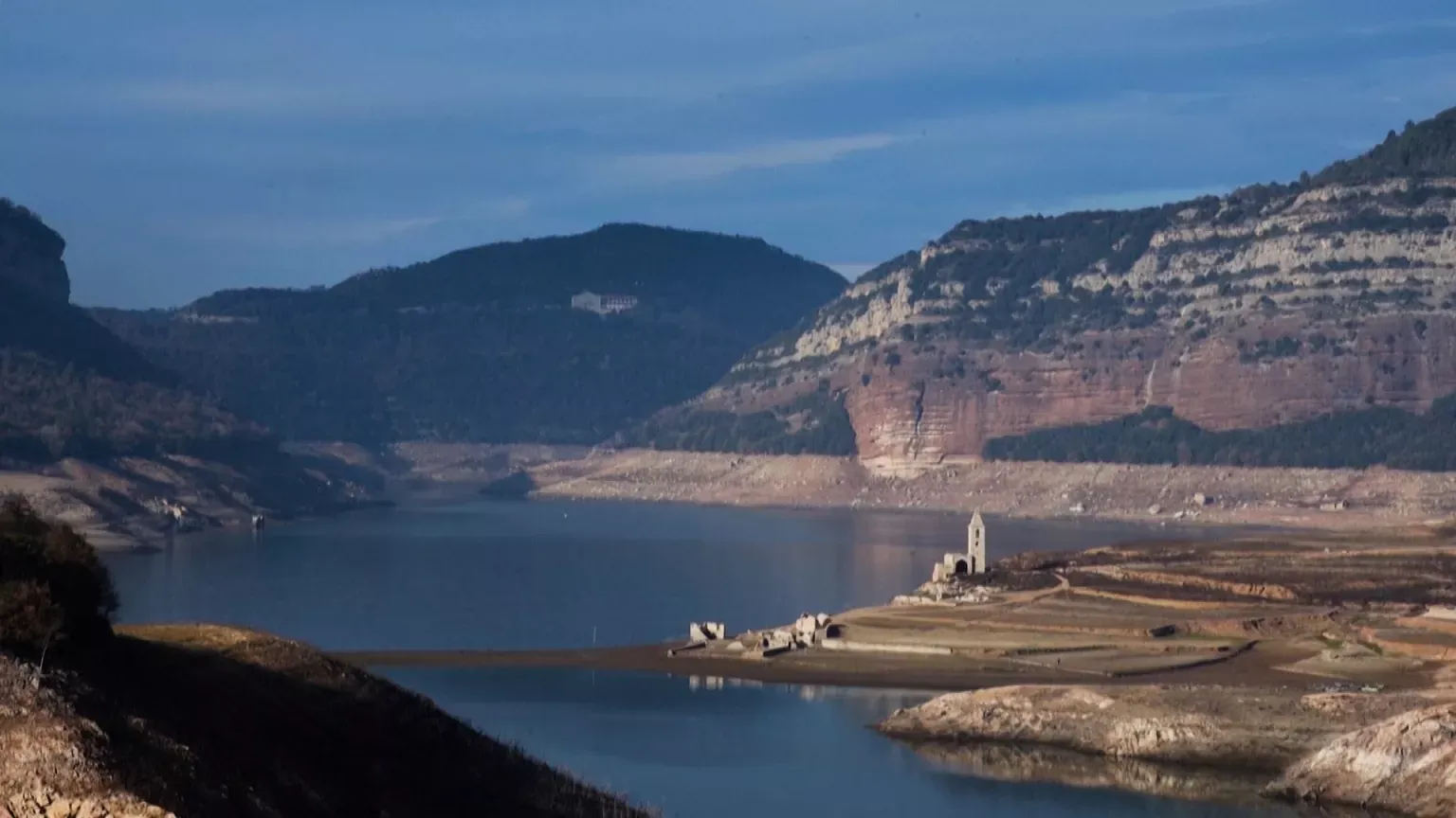 A Spanish reservoir showing cracked earth and very low water levels, illustrating the Spain water crisis.